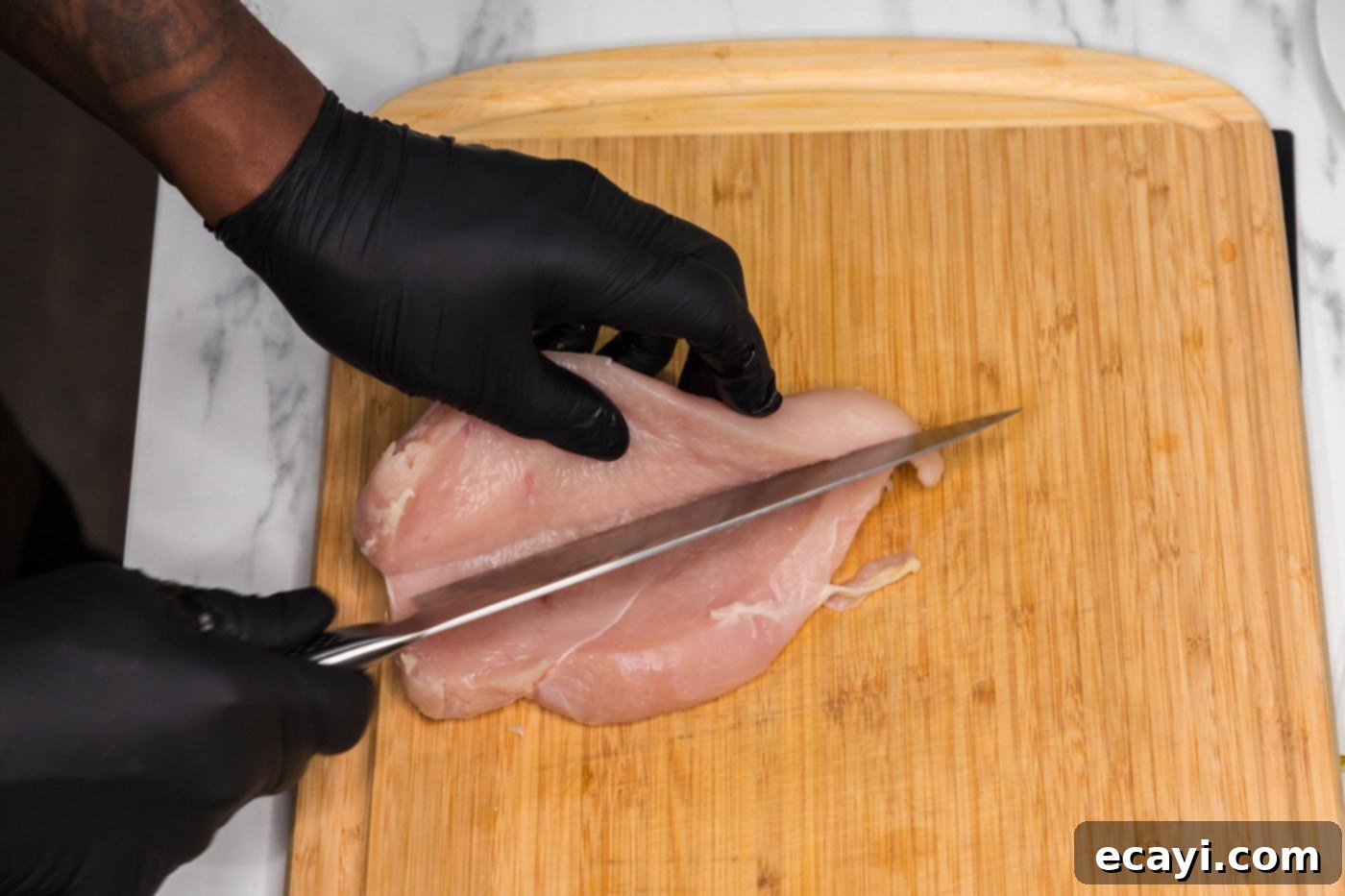 Philly Chicken Cheesesteak 5 Expertly butterflying a thick chicken breast with a knife for even cooking.