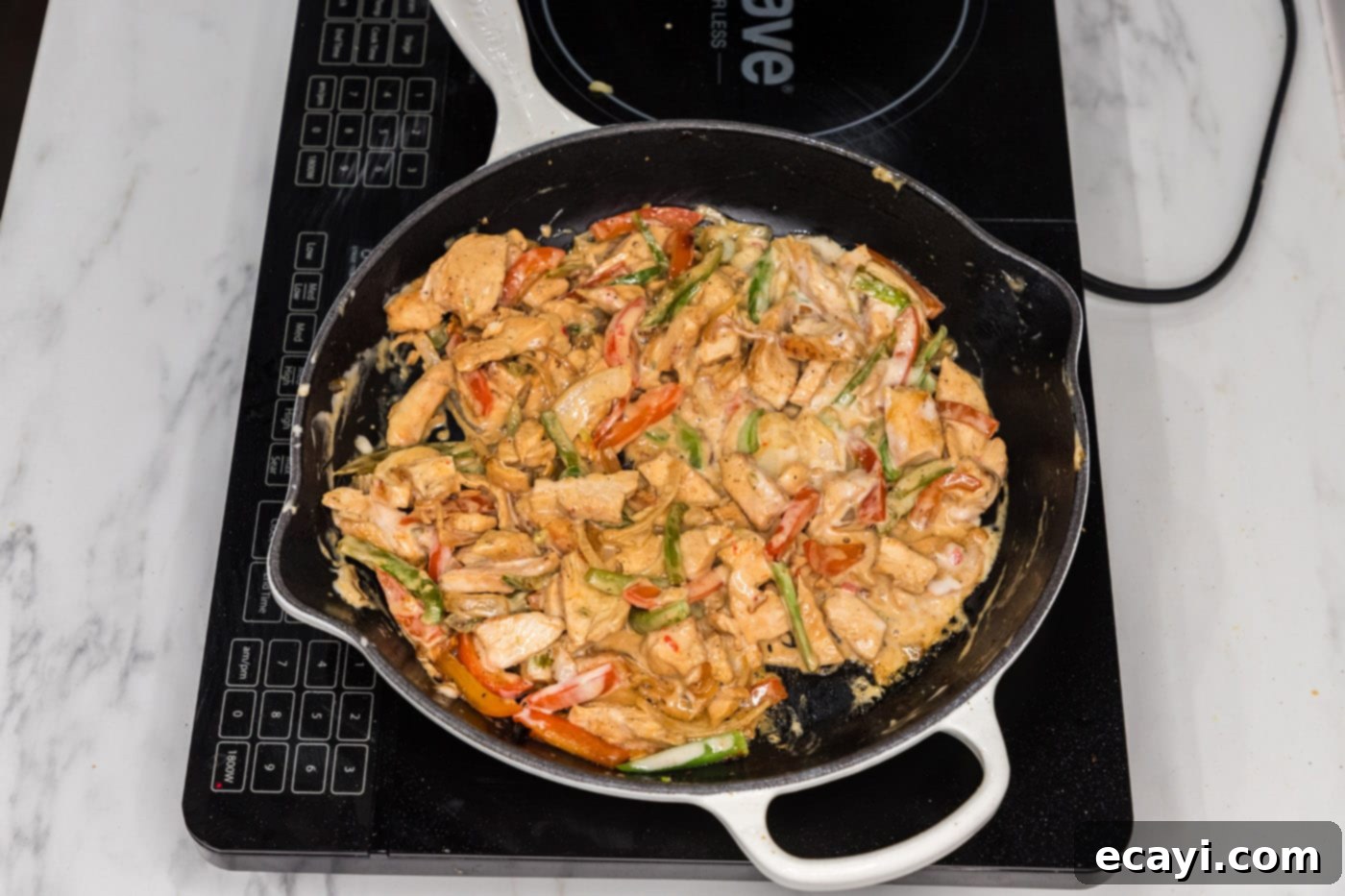Philly Chicken Cheesesteak 9 Creamy queso dip being stirred into the chicken and vegetable mixture in a skillet, creating a luscious filling for the sandwiches.