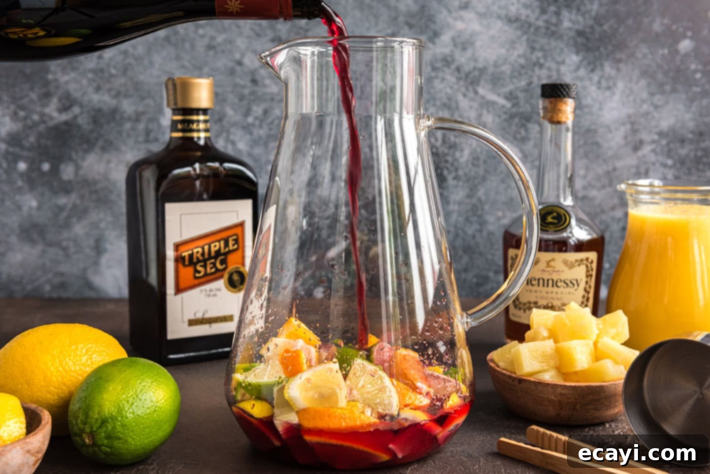 Mexican Fiesta Sangria 6 Pouring a bottle of Red Moscato wine into a pitcher filled with fresh citrus slices