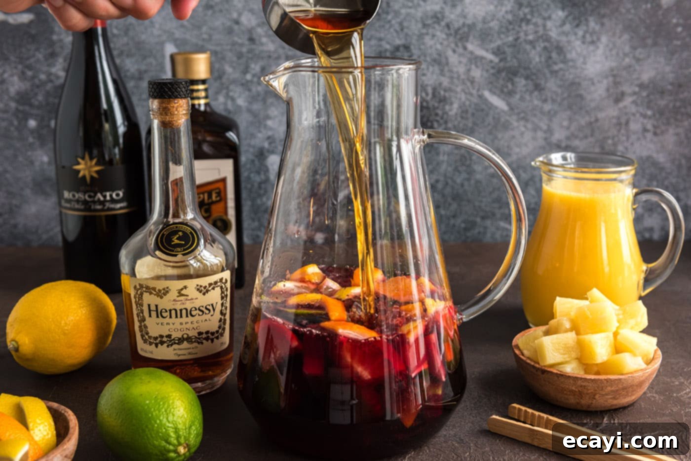 Mexican Fiesta Sangria 7 Adding brandy to the red moscato and fruit mixture in a large pitcher for sangria