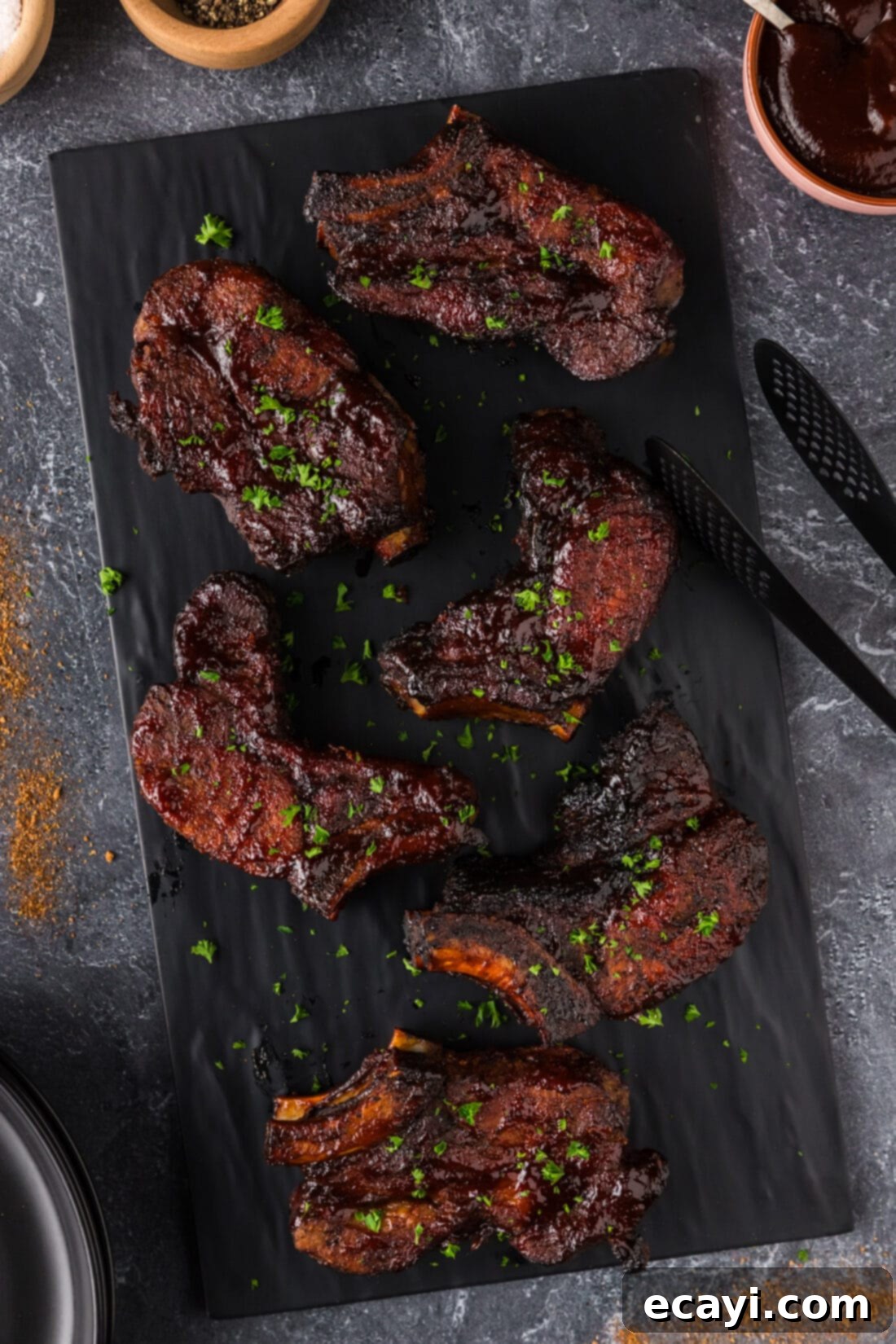 Down-Home Country Ribs 3 Country Style Ribs on a black platter, glistening with barbecue sauce.