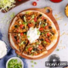 Fiesta Taco Pizza 11 Taco Pizza cut into slices topped with sour cream and fresh herbs, ready to be served.