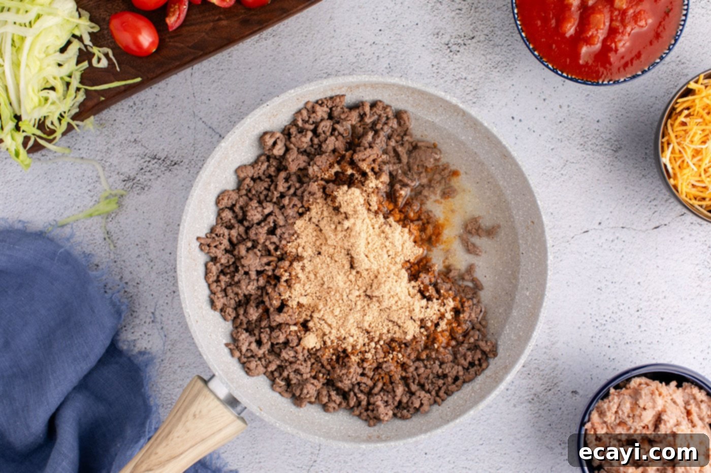 Fiesta Taco Pizza 6 Taco seasoning and water added to the cooked ground beef in a skillet, simmering.