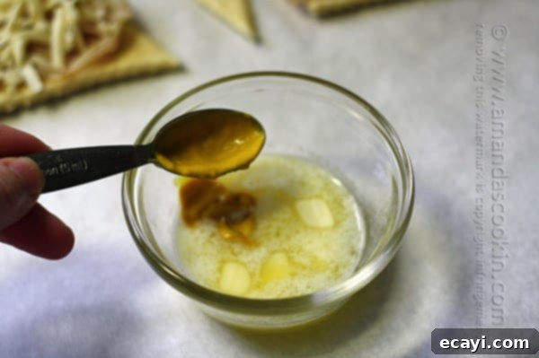 Preparing the mustard butter sauce for Turkey Pepper Jack Roll Ups. Mixing mustard into melted butter for the glaze