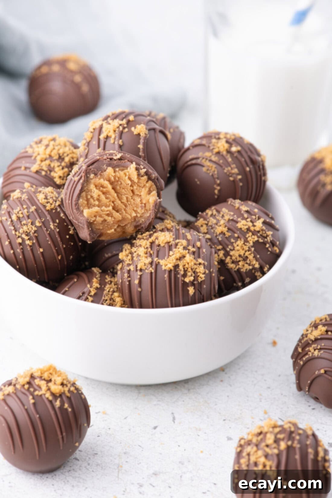 Peanut Butter Truffle Bites 2 Bowl of Nutter Butter Balls with more resting on the table, garnished with cookie crumbs and chocolate drizzle