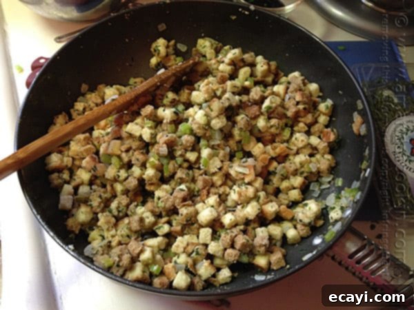 Aromatic Herb Stuffing 7 A close up photo of cubed stuffing with chopped onions and celery in a skillet.