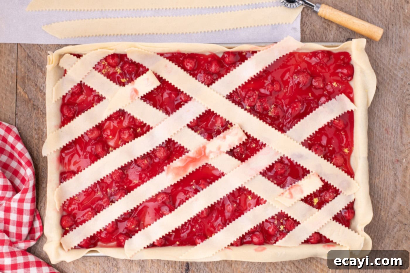 Sheet Pan Cherry Pie 13 arranging pie crust weave on top of cherry pie filling