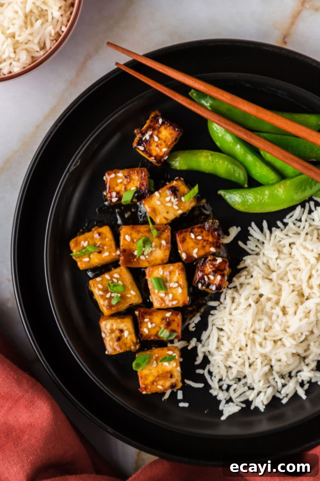 Sticky Honey Garlic Tofu 2 Close up photo of Honey Garlic Tofu on a plate with rice and snap peas