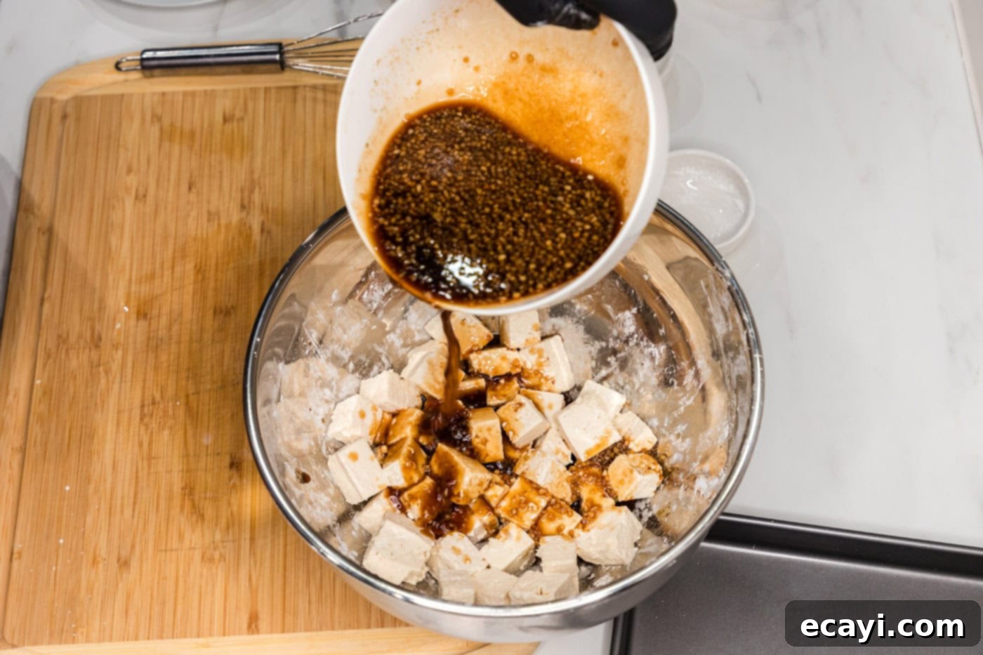 Sticky Honey Garlic Tofu 8 pouring sauce over cornstarch coated tofu cubes
