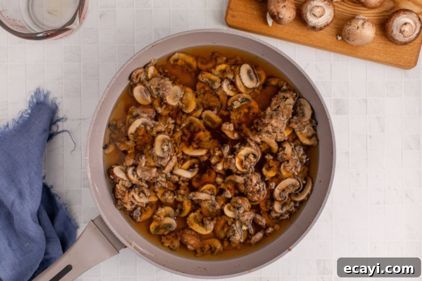 Hearty Salisbury Steak Meatballs 12 beef broth and Worcestershire sauce being poured into the mushroom sauce in the skillet
