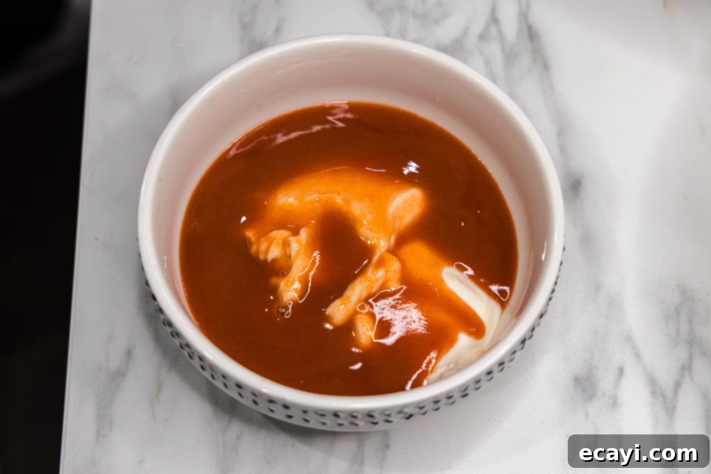 Fiery Buffalo Chicken Bowl 6 hot sauce and mayonnaise being whisked together in a small bowl to create the buffalo dressing
