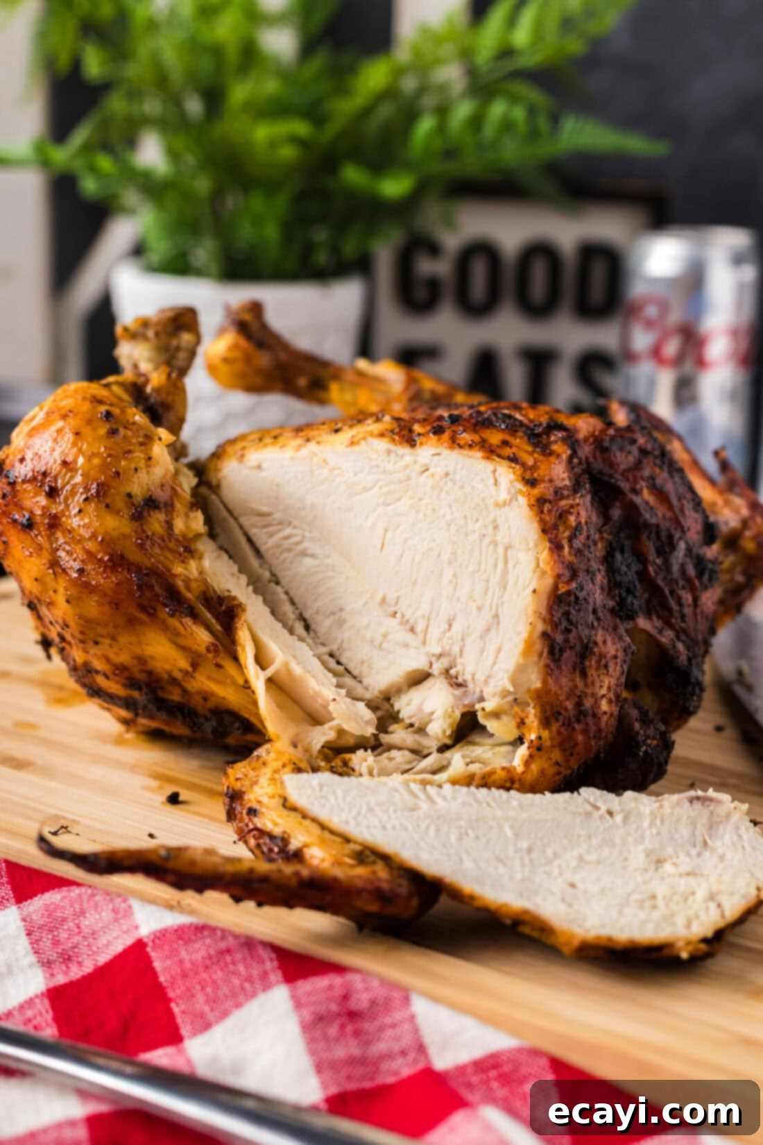 Juicy Beer-Infused Roasted Chicken 10 Slice of Beer Can Chicken resting on a wooden cutting board with the rest of the Beer Can Chicken behind it