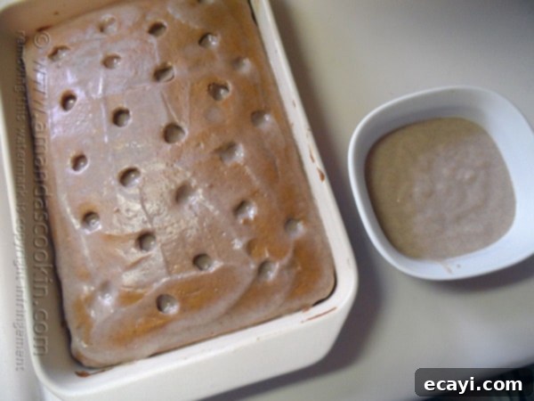 Autumn Pumpkin Pudding Poke Cake 11 An overhead view of a pumpkin cake in a baking dish, completely covered with a smooth layer of pudding on top.
