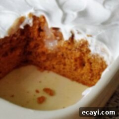 Autumn Pumpkin Pudding Poke Cake 15 A close up photo of a pumpkin pudding poke cake in a baking dish with a square missing.