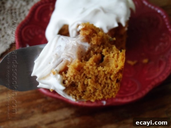 Autumn Pumpkin Pudding Poke Cake 4 A close up photo of a single slice of pumpkin pudding poke cake on a vibrant red plate, garnished with whipped topping.