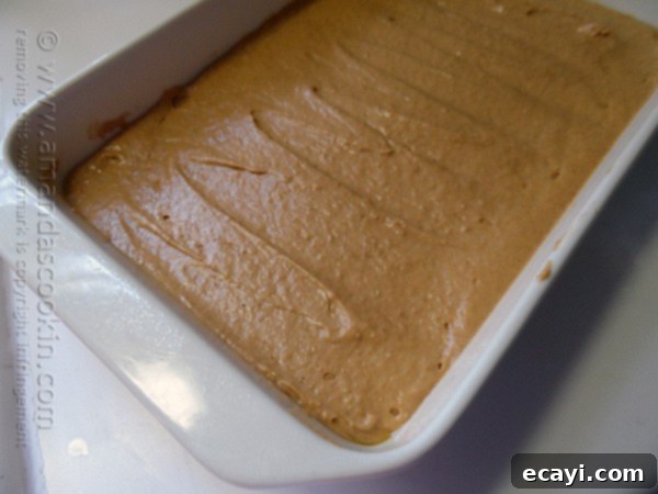 Autumn Pumpkin Pudding Poke Cake 5 A photo of smooth pumpkin cake batter being poured into a prepared baking dish, ready for the oven.
