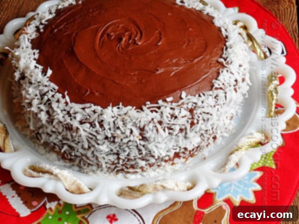 Blissful Almond Coconut Snowflake Cake 2 A beautifully frosted Almond Joy Coconut Snowflake Cake, garnished with flaked coconut, resting on a pristine white cake stand, ready for holiday celebrations.