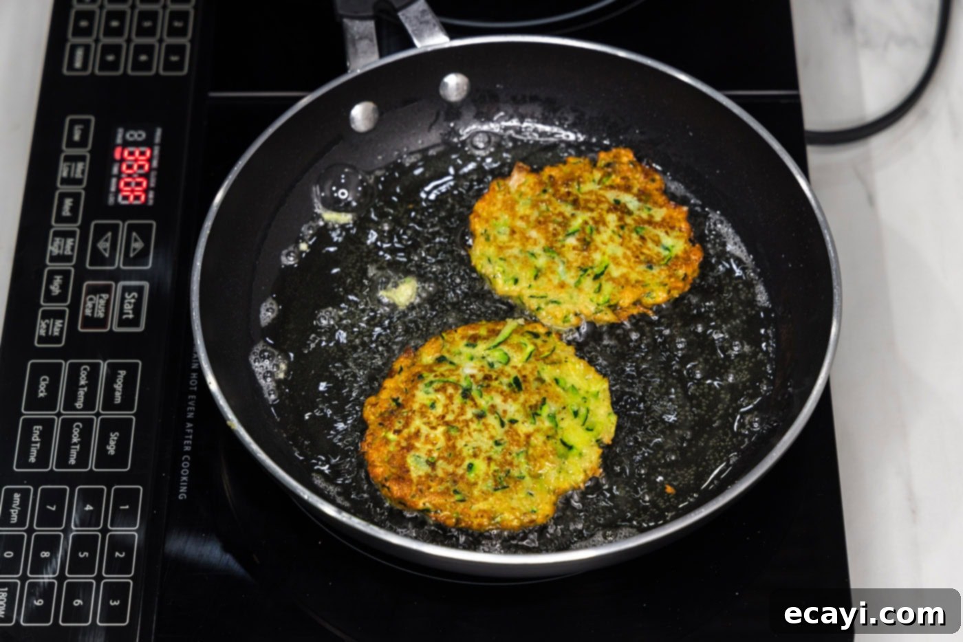 Crispy Zucchini Delights 11 fried zucchini fritters in a skillet of oil