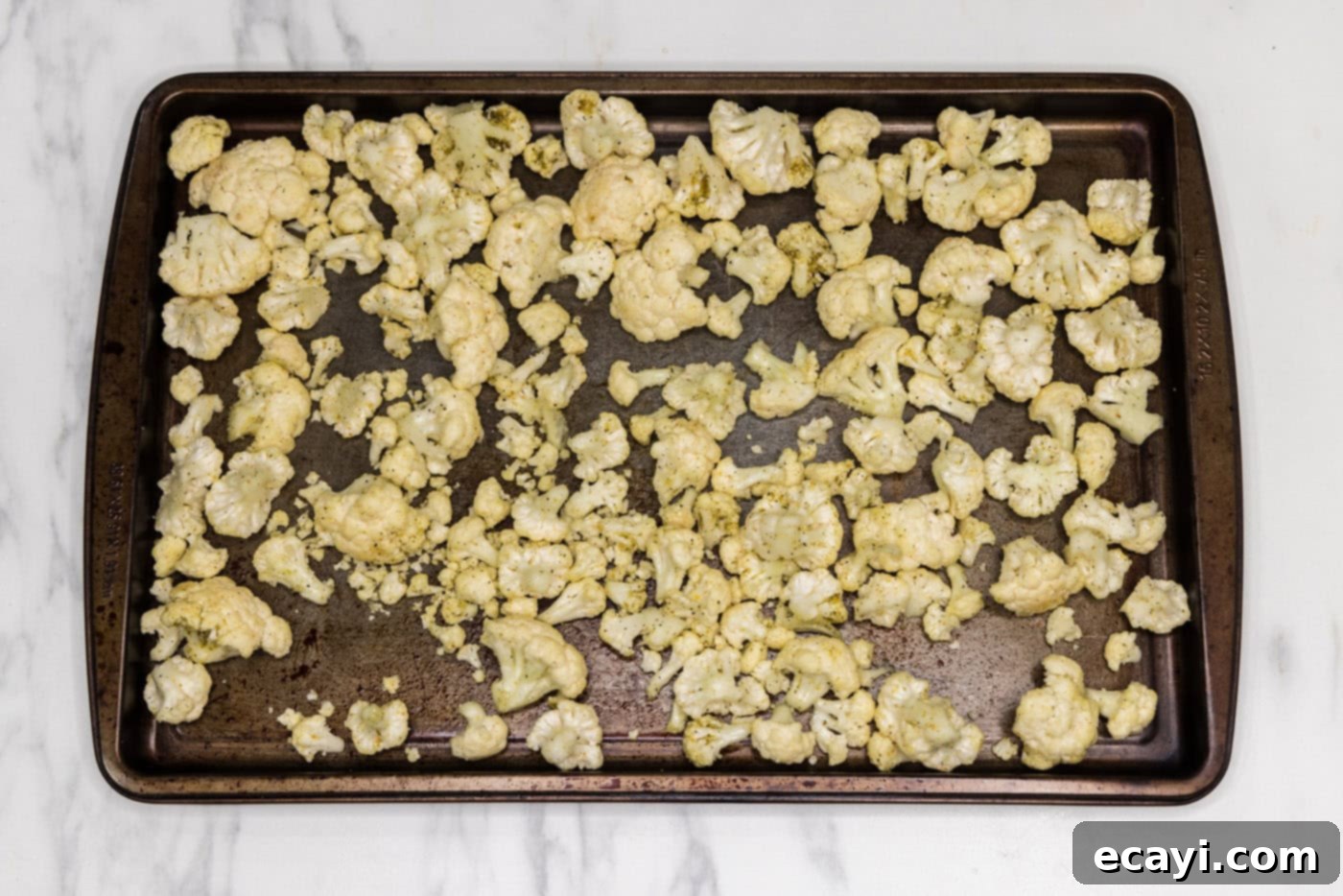 Zesty Cauliflower Medley 7 Cauliflower florets spread in a single layer on a baking sheet, ready for roasting.