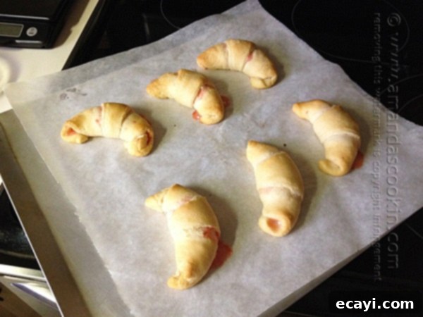 Festive White Chocolate Candy Cane Cookies 11 Freshly baked white chocolate candy cane crescents, glistening with a sweet glaze and adorned with larger crushed peppermint pieces, ready to be served.
