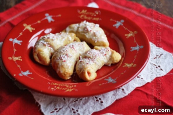 Festive White Chocolate Candy Cane Cookies 5 An overhead view of several freshly baked white chocolate candy cane crescents artfully arranged on a festive red plate, ready to be enjoyed.