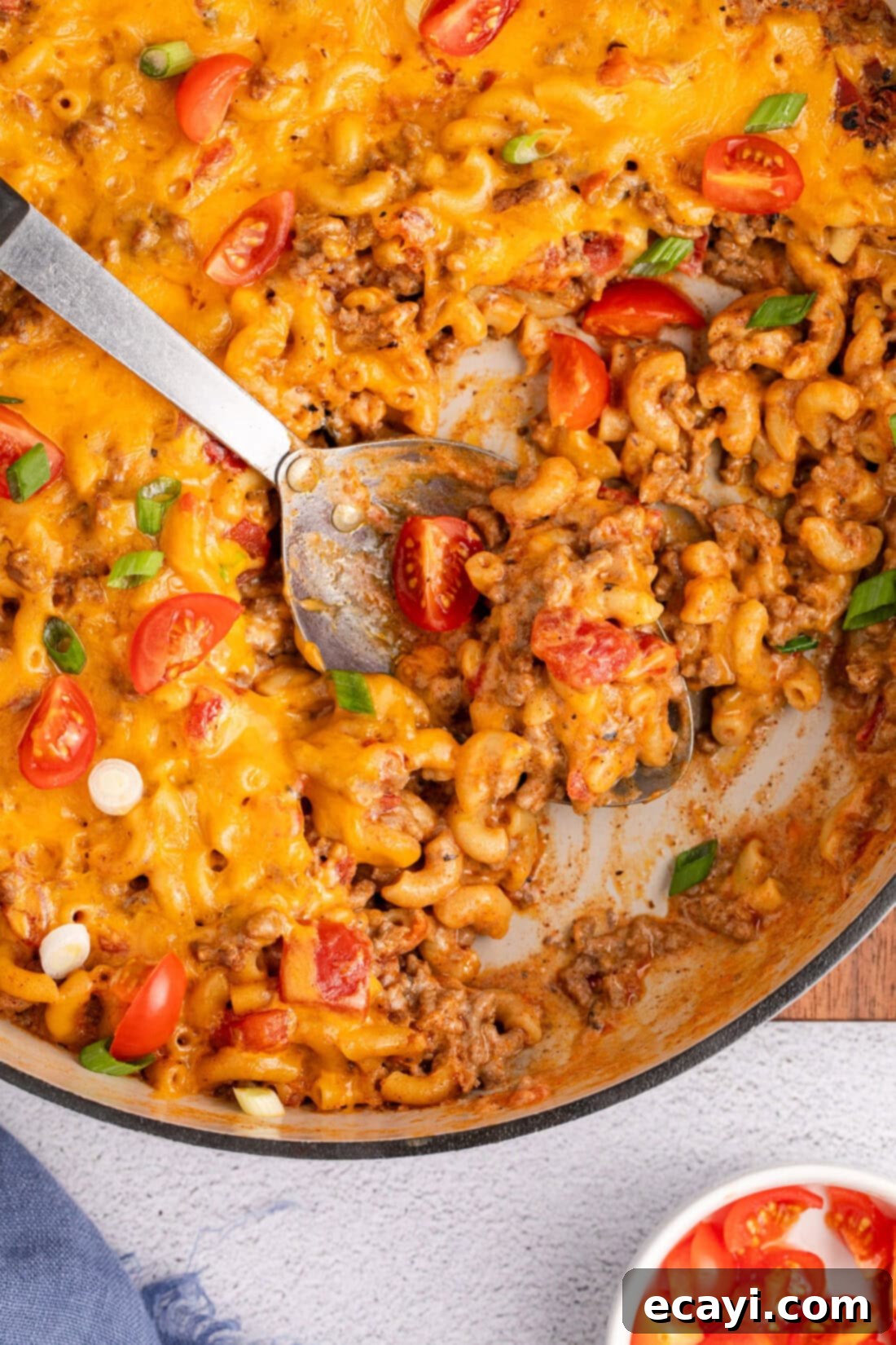 Taco Mac 'n' Cheese 3 Close up photo of a spoon in a skillet of Taco Macaroni and Cheese, highlighting the melted cheese and seasoned beef.