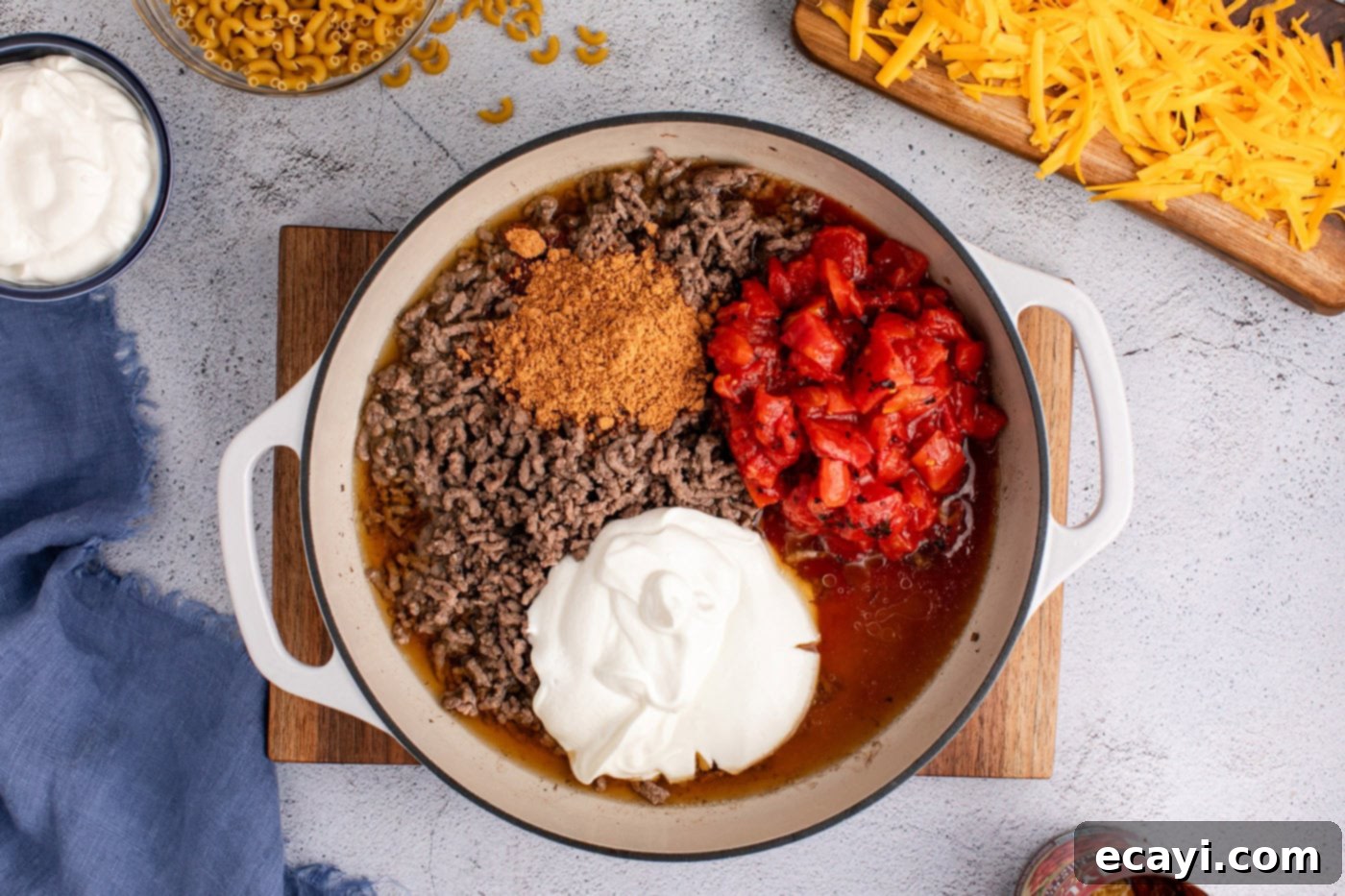 Taco Mac 'n' Cheese 6 diced tomatoes, taco seasoning, and sour cream added to skillet with ground beef, ready to be combined.