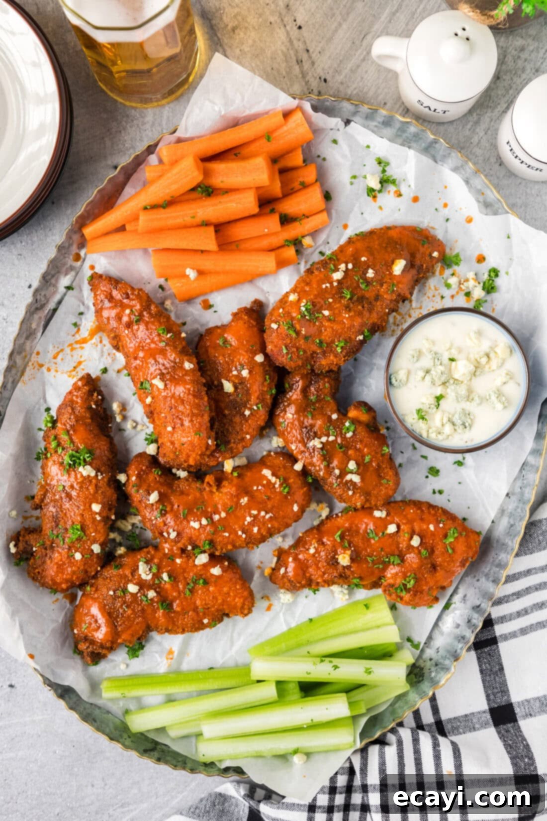 Signature Buffalo Chicken Strips 2 Crispy Buffalo Chicken Tenders served on a parchment-lined platter with carrots, celery sticks, and a side of ranch dressing.