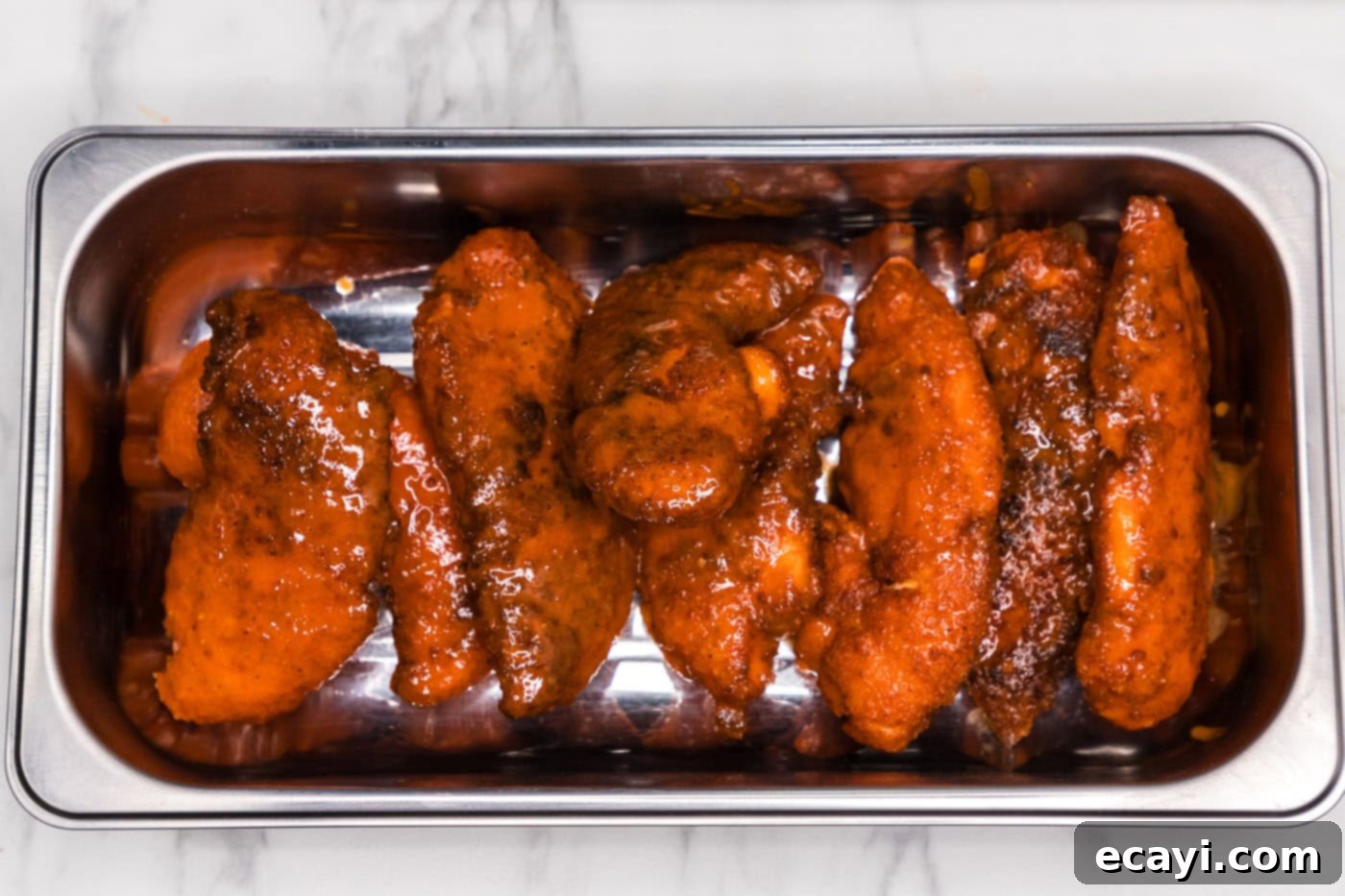 Signature Buffalo Chicken Strips 14 Finished buffalo chicken tenders laid out in a pan, fully coated with the spicy sauce.