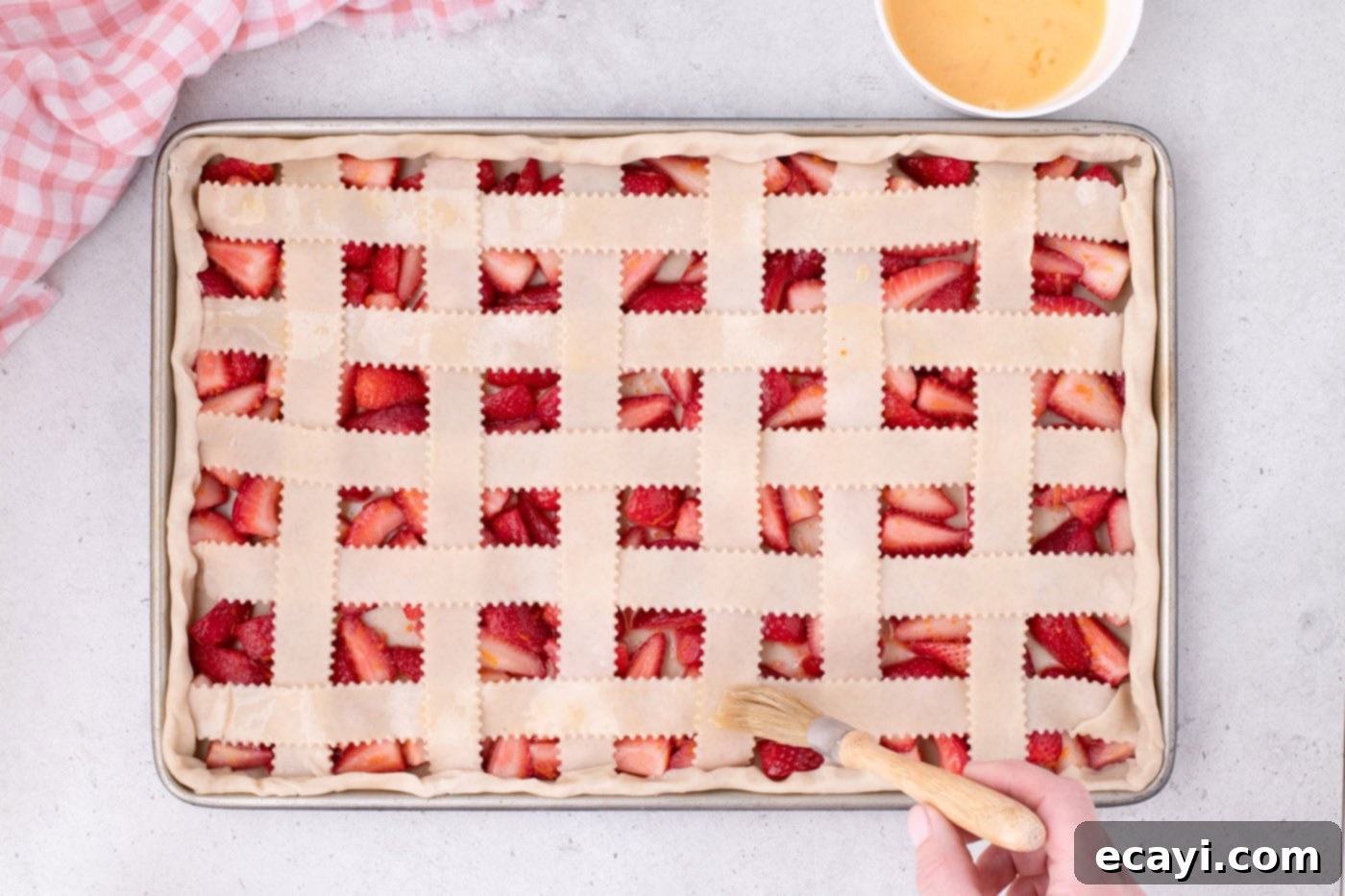 Strawberry Sheet Pan Delight 18 brushing the strawberry slab pie lattice top with egg wash and sprinkling turbinado sugar