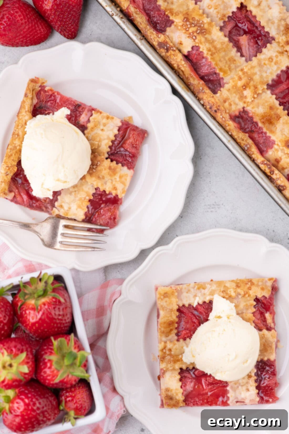 Strawberry Sheet Pan Delight 20 Two beautiful slices of Strawberry Slab Pie on white plates, each topped with a scoop of vanilla ice cream.