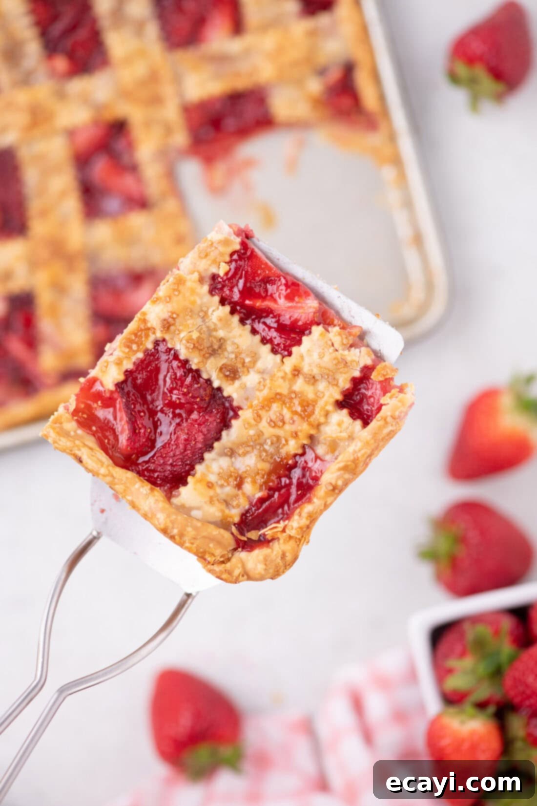 Strawberry Sheet Pan Delight 3 Spatula holding up a generous slice of Strawberry Slab Pie, showing the filling and crust layers.
