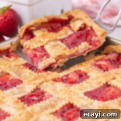 Strawberry Sheet Pan Delight 21 Slice of Strawberry Slab Pie being removed from the pan, showing the golden crust and juicy filling.