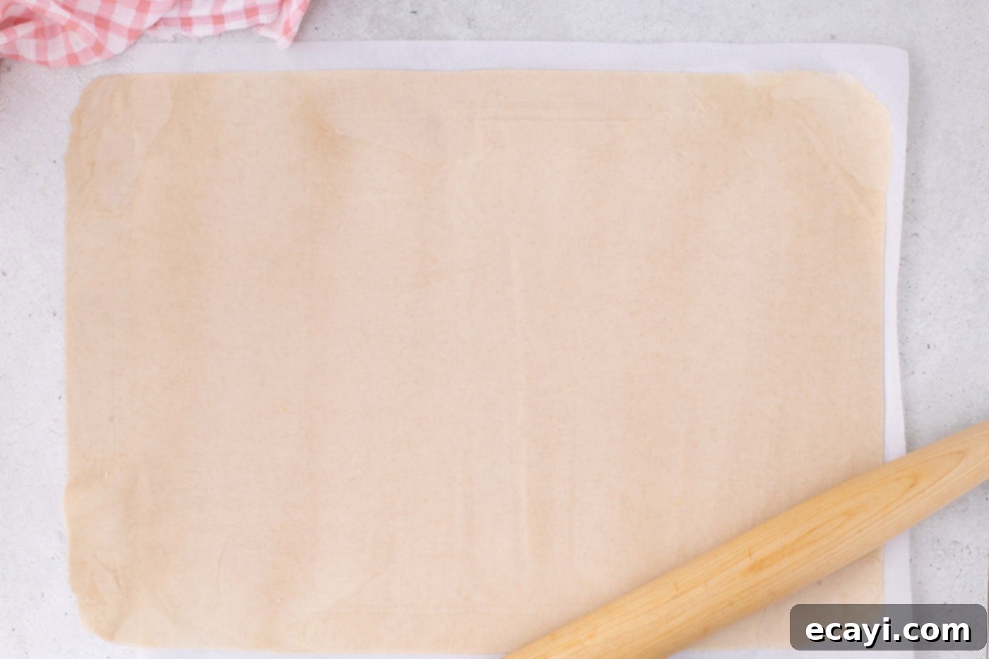 Strawberry Sheet Pan Delight 9 slab pie crust rolled out to the correct size on a parchment-lined surface with a rolling pin