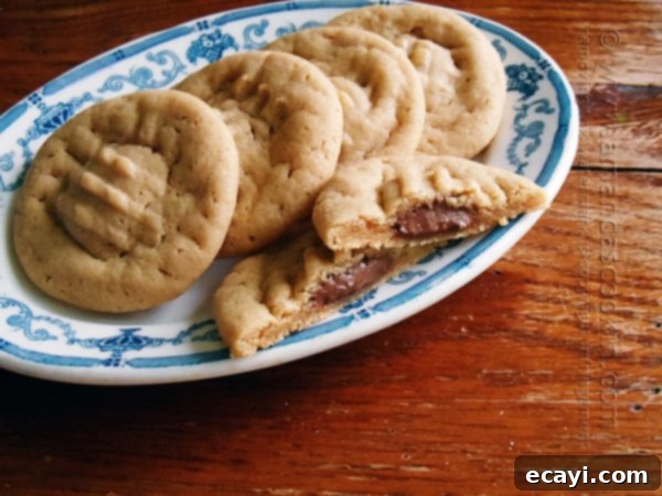 Chocolate-Stuffed Peanut Butter Perfection 4 A top-down view of a plate piled high with golden-brown chocolate-stuffed peanut butter cookies, each featuring the classic criss-cross fork pattern on top. The image conveys the abundance and deliciousness of a fresh batch of homemade cookies.