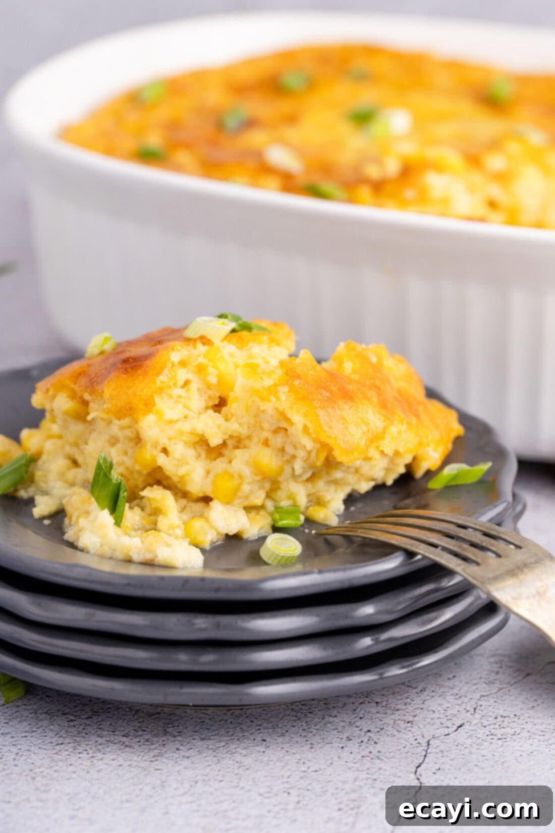 Creamy Golden Corn Bake 11 A scoop of homemade Corn Pudding served on a white plate with a fork, ready to be enjoyed