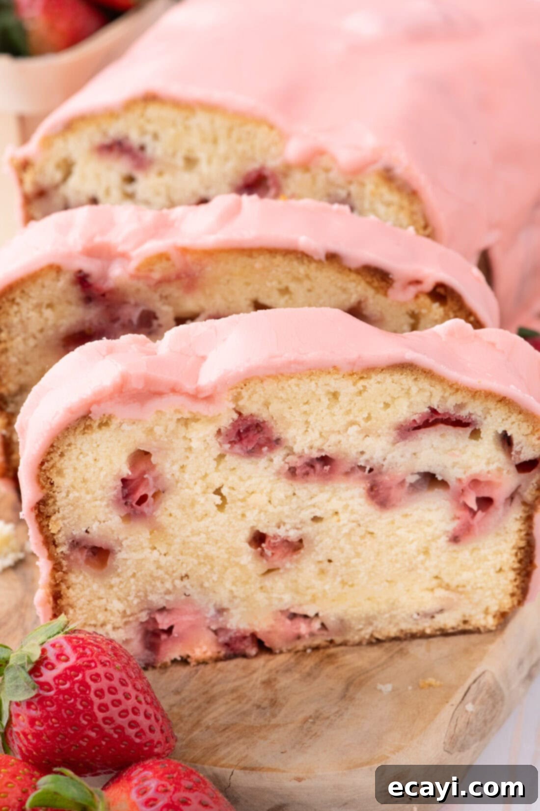 Luscious Strawberry Pound Cake 2 Slices of moist Strawberry Pound Cake on a rustic wooden board, topped with pink glaze and fresh berries.