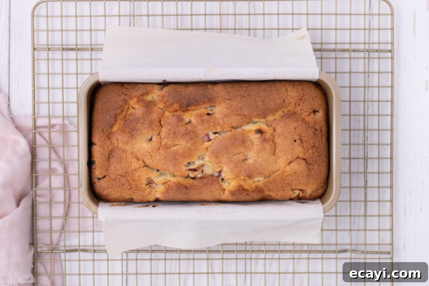 Luscious Strawberry Pound Cake 13 A freshly baked strawberry pound cake, golden brown and perfectly risen, cooling on a wire rack with the loaf pan visible.