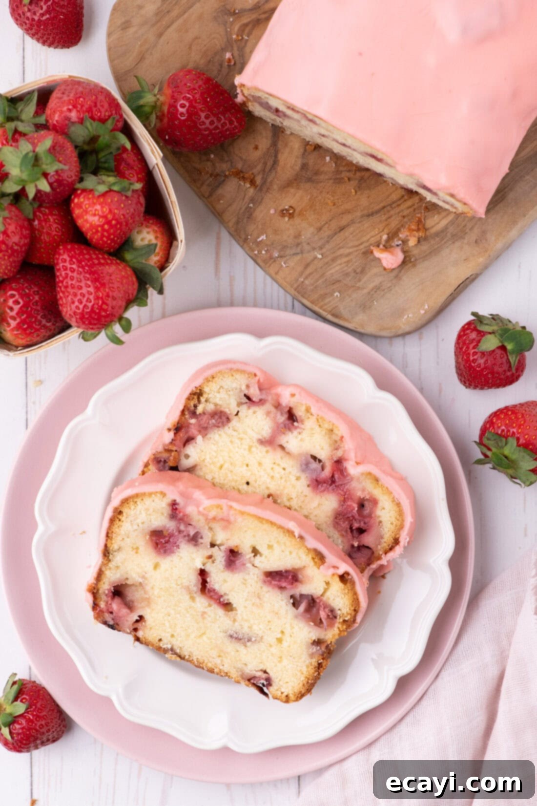 Luscious Strawberry Pound Cake 18 Two enticing slices of Strawberry Pound Cake on a white plate, adorned with a delicate pink glaze and a few fresh berries.