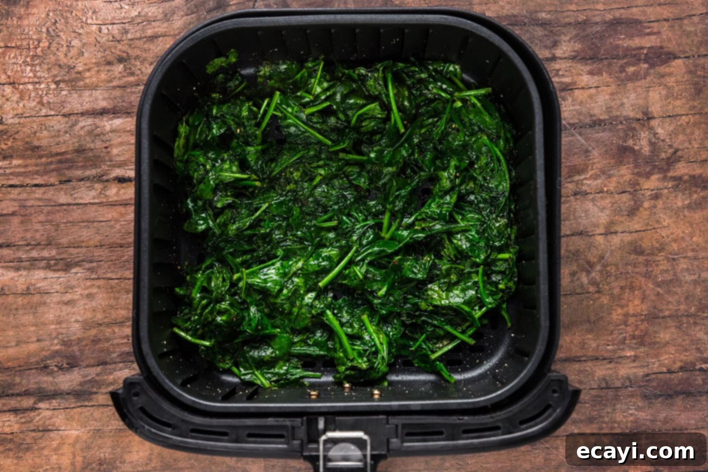 cooked spinach in an air fryer basket