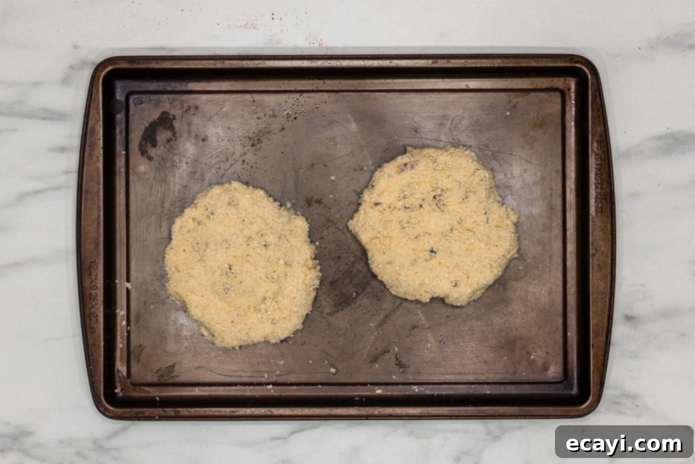 Zesty Shrimp Burger 13 Three breaded shrimp burger patties neatly arranged on a baking sheet, ready for frying.