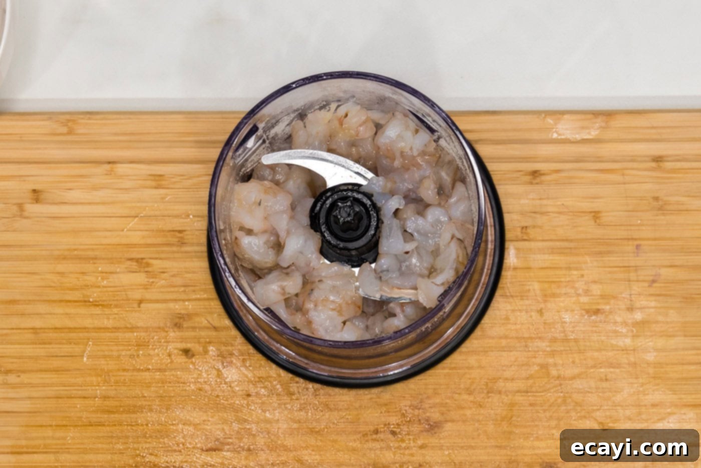Zesty Shrimp Burger 7 Raw shrimp, butter, Dijon mustard, Old Bay, and garlic salt in a mini food chopper, ready to be blended.
