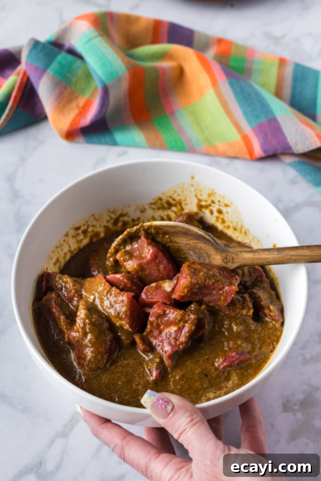 Signature Bourbon Marinade 3 Spoon stirring steak and Bourbon Marinade in a bowl