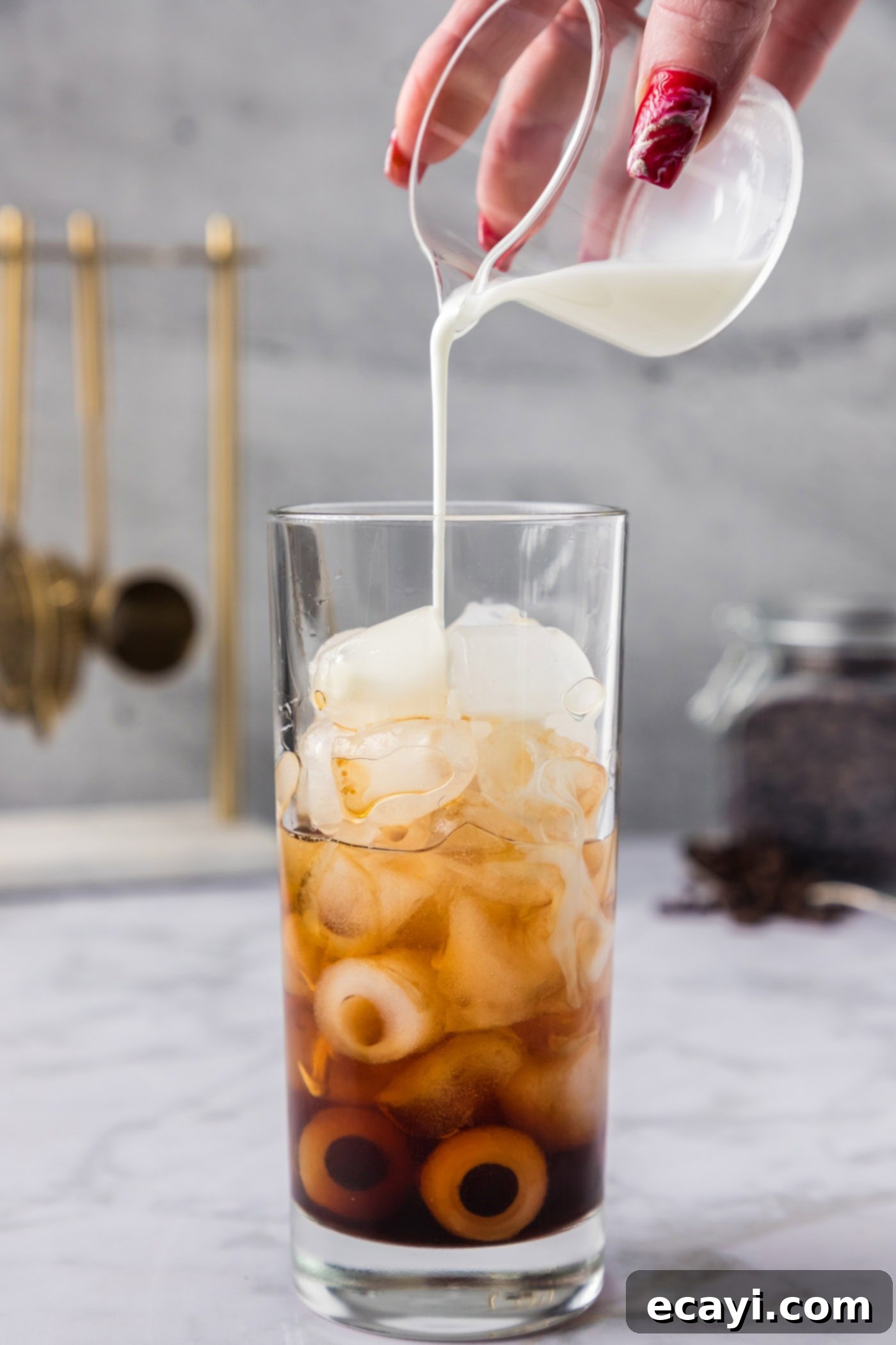 Cold Buzz Coffee 5 Pouring half and half into a glass with ice, Kahlua, and vanilla vodka