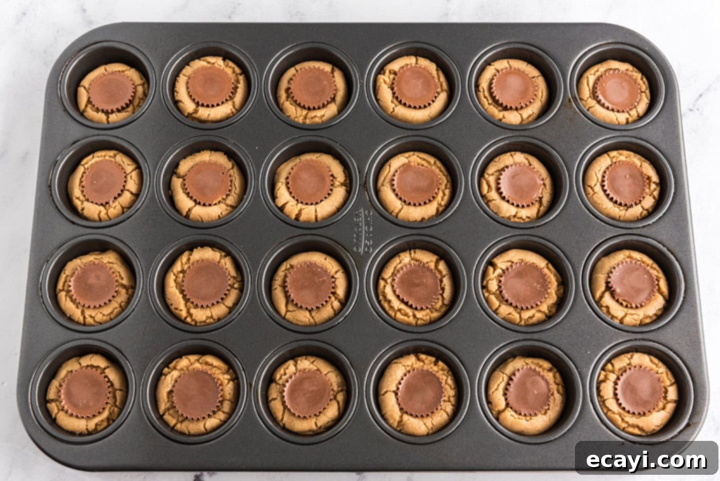 Reese's Peanut Butter Cup Stuffed Cookies 12 baked reeses peanut butter cup cookies in a mini muffin pan