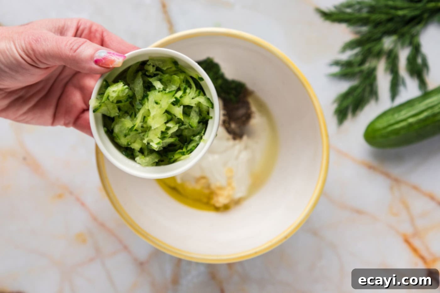 Classic Tzatziki Dip 7 adding shredded cucumber to a bowl of tzatziki sauce ingredients