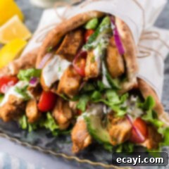 Authentic Chicken Shawarma 11 Close up photo of Chicken Shawarma pita wraps stacked on top of each other, highlighting the golden chicken and fresh fillings.
