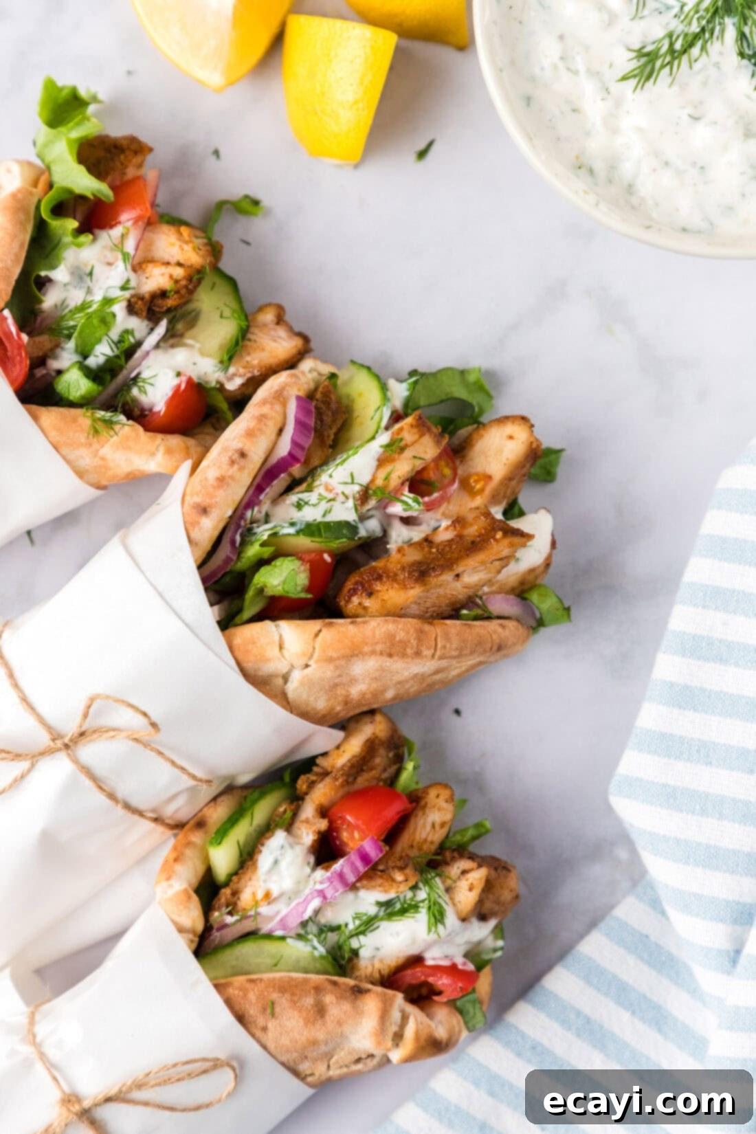 Authentic Chicken Shawarma 3 A close-up shot of a perfectly assembled chicken shawarma wrap, generously filled with seasoned chicken, fresh vegetables, and a creamy drizzle of tzatziki sauce, all tucked into warm pita bread.
