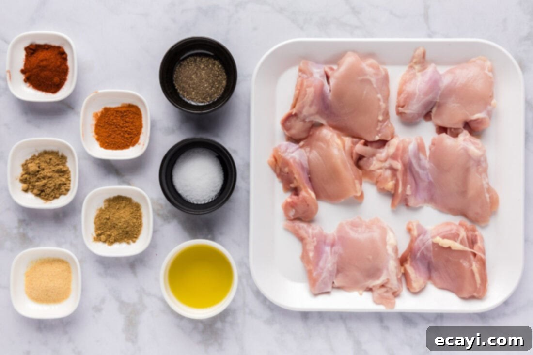 Authentic Chicken Shawarma 4 A flat lay of all the fresh ingredients needed to prepare homemade chicken shawarma, including raw chicken, a variety of colorful spices, fresh vegetables, and pita bread.