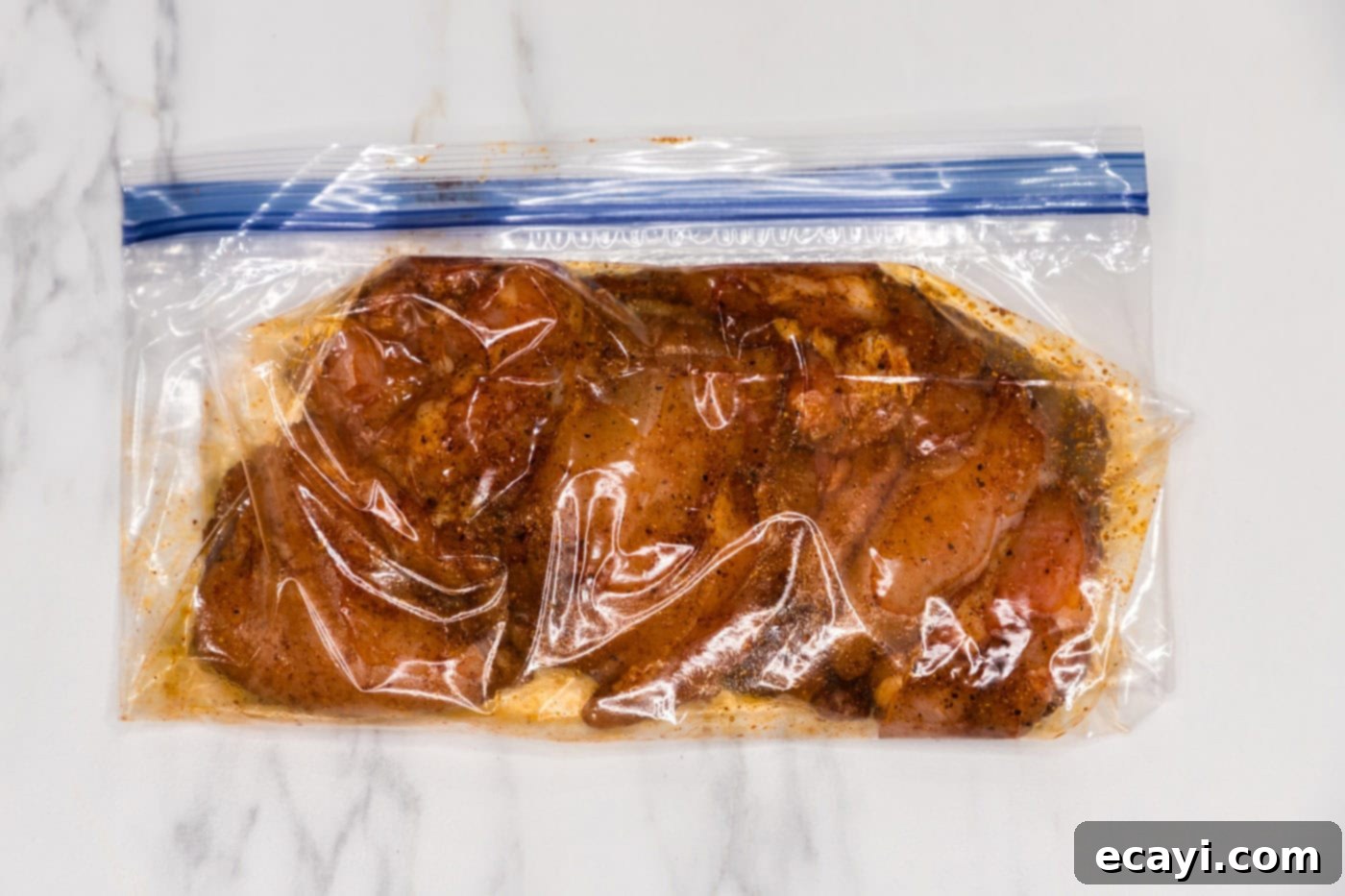 Authentic Chicken Shawarma 6 Marinating chicken thighs in a clear plastic zip-top bag, coated evenly with a rich, colorful spice blend, ready to absorb all the delicious flavors.